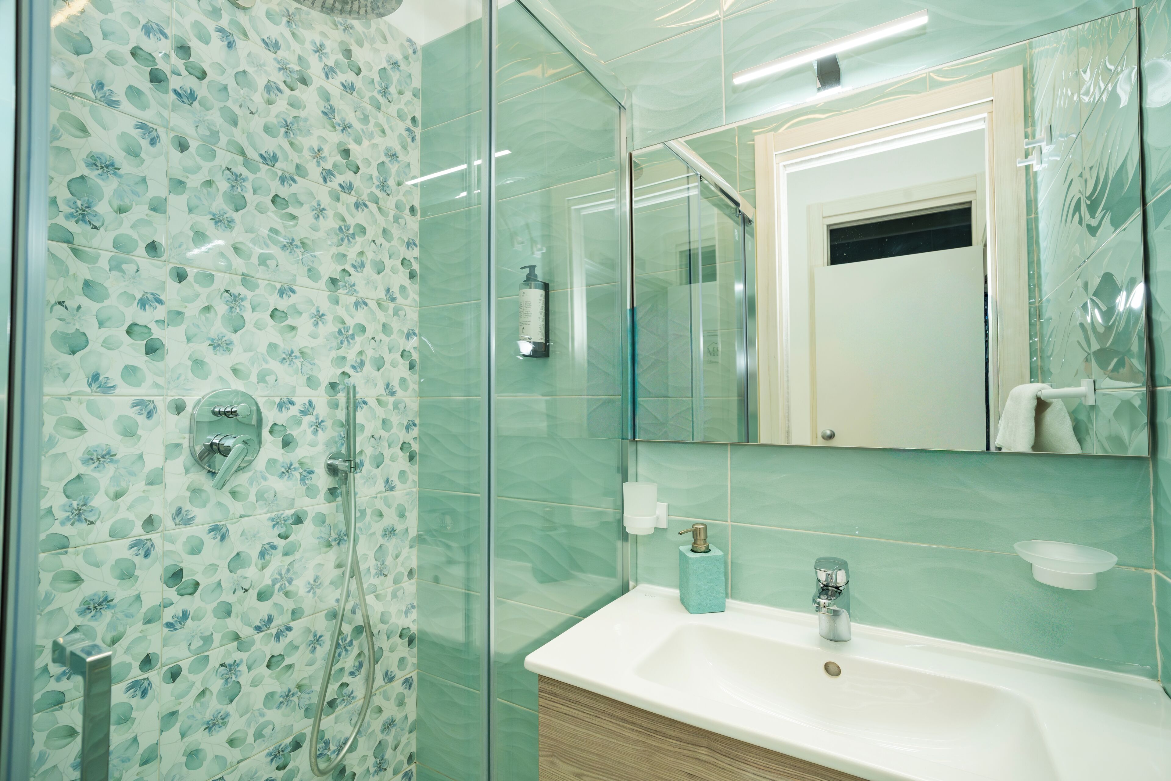 Une salle de bain avec une douche, un lavabo et un miroir.