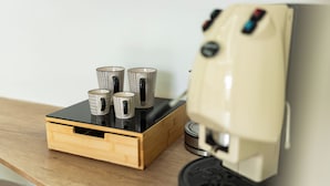 A coffee machine with four cups on a wooden table.