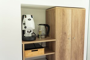 Un armario de madera con un estante que contiene una cafetera y un hervidor.