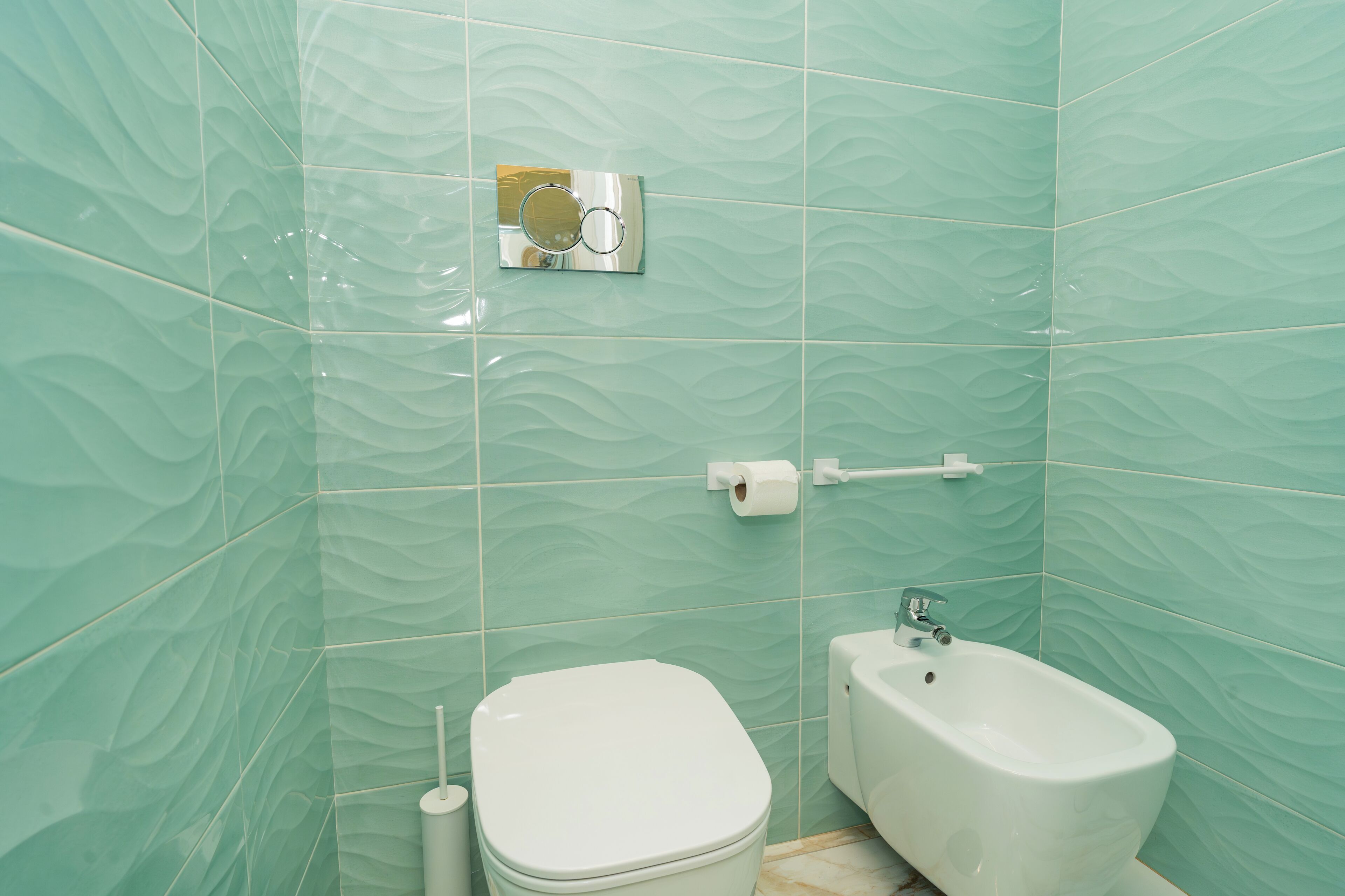 A bathroom with a toilet, bidet, and a towel rack.
