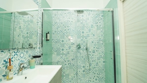A bathroom with a shower, a sink, and a mirror.