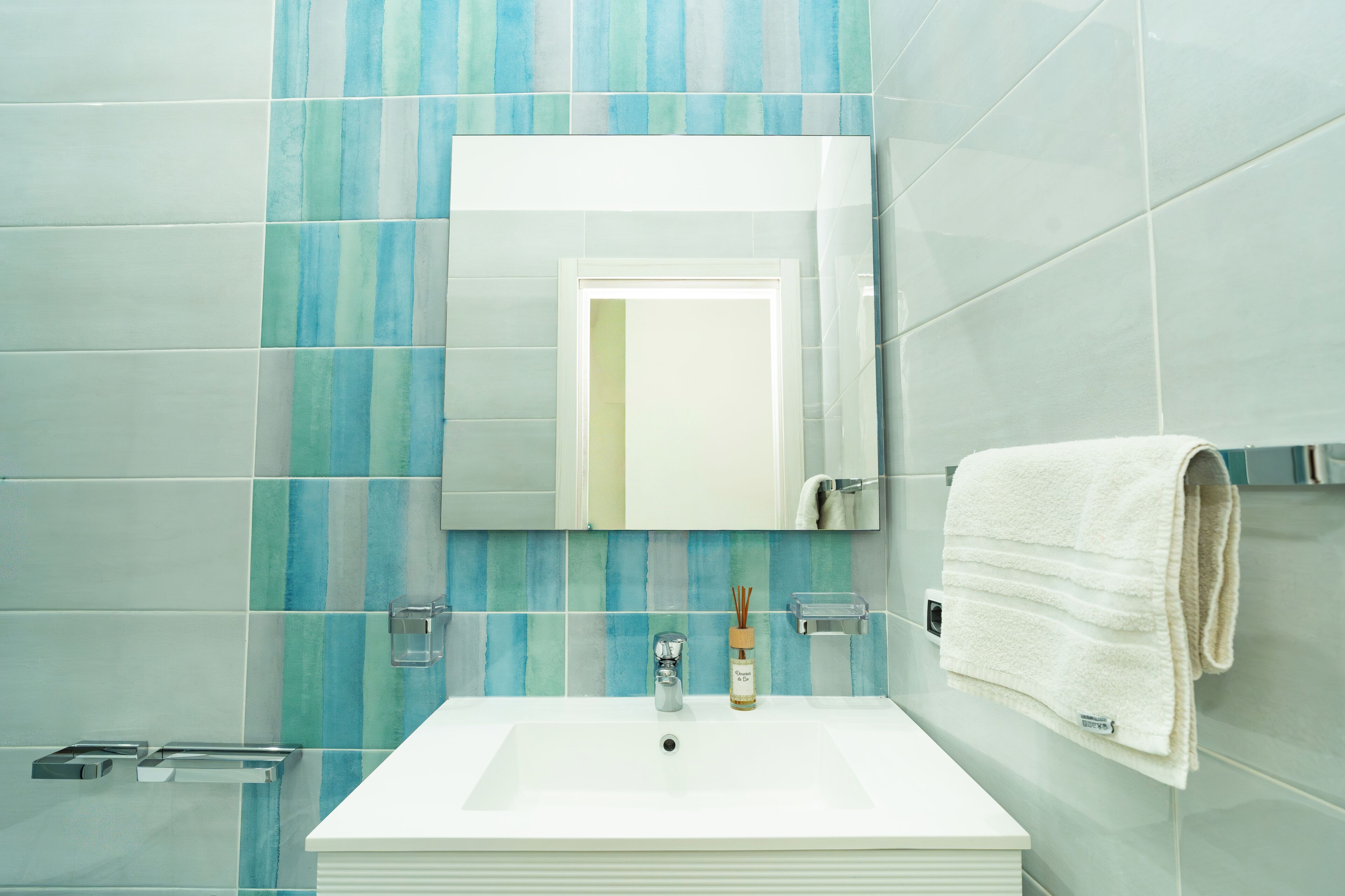 Ein Badezimmer mit einem weißen Waschbecken, einem Spiegel darüber und einem Handtuch an der Wand.