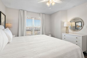 Une chambre d’hôtel avec un grand lit, une commode, un miroir et une fenêtre avec des stores.