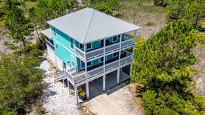 Ein zweistöckiges Strandhaus mit einem Balkon im Erdgeschoss und einer überdachten oberen Ebene.