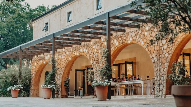 A stone building with arched entrances, a reception desk, and potted plants. - Avianto Pty Ltd (Muldersdrift)