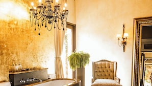 A luxurious bathroom with a freestanding bathtub, a classic chair, and a chandelier. - Avianto Pty Ltd (Muldersdrift)