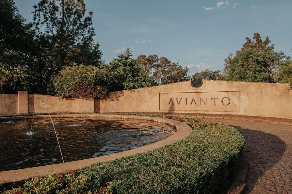 A landscaped area with a circular water feature and a wall with the word 'AVIANTO' on it.