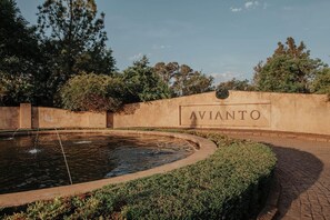 A landscaped area with a circular water feature and a wall with the word 'AVIANTO' on it.
