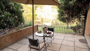 An outdoor patio with two tables, chairs, a metal umbrella, and a bottle of champagne. - Avianto Pty Ltd (Muldersdrift)