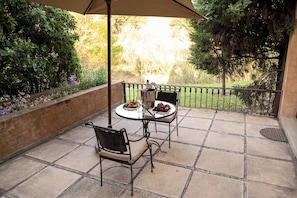 An outdoor patio with two tables, chairs, a metal umbrella, and a bottle of champagne. - Avianto Pty Ltd (Muldersdrift)