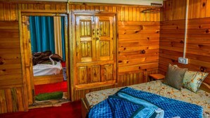 A wooden room with a bed, a wardrobe, and a small table. - Neervan Resort (Gushaini)