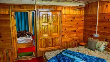 Una habitación de madera con una cama, un armario y una mesita.