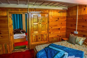 A wooden room with a bed, a wardrobe, and a small table. - Neervan Resort (Gushaini)