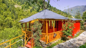 A wooden structure with a porch, surrounded by lush greenery and hills. - Neervan Resort (Gushaini)