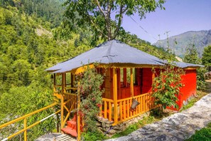 A wooden structure with a porch, surrounded by lush greenery and hills. - Neervan Resort (Gushaini)