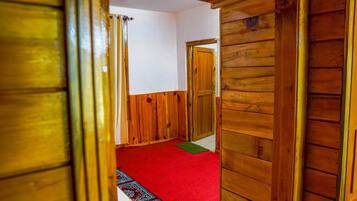 A wooden interior hallway with a red carpet, wooden doors, and a patterned rug.