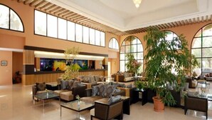 Un hall d’entrée spacieux avec un comptoir de réception, des coins salon confortables et de grandes fenêtres.