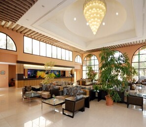 A spacious lobby with a reception desk, comfortable seating areas, and large windows. - Paradis Palace (Hammamet Sud)