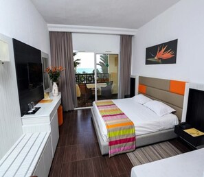 A hotel room with a bed, a TV, a desk, and a view of the outside. - Paradis Palace (Hammamet Sud)