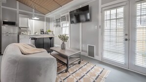 A modern kitchen with a built-in oven, a coffee machine, and a TV mounted on the wall. - The Cozy Cottage - Private Yard • Pet Friendly • Seminole Heights (Tampa)