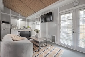 A modern kitchen with a built-in oven, a coffee machine, and a TV mounted on the wall.