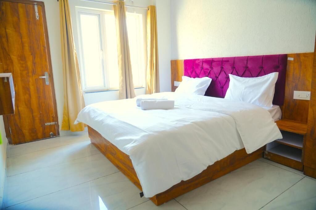 Habitación de hotel con cama, cortinas y ventana.