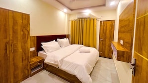 Quarto de hotel com cama, guarda-roupa e uma pequena mesa de madeira.