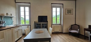 Cozinha com mesa de jantar, televisão e uma cadeira.