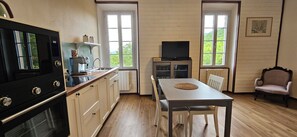 Een compacte keuken met een kookplaat, spoelbak en een eethoek met een tafel en stoelen.
