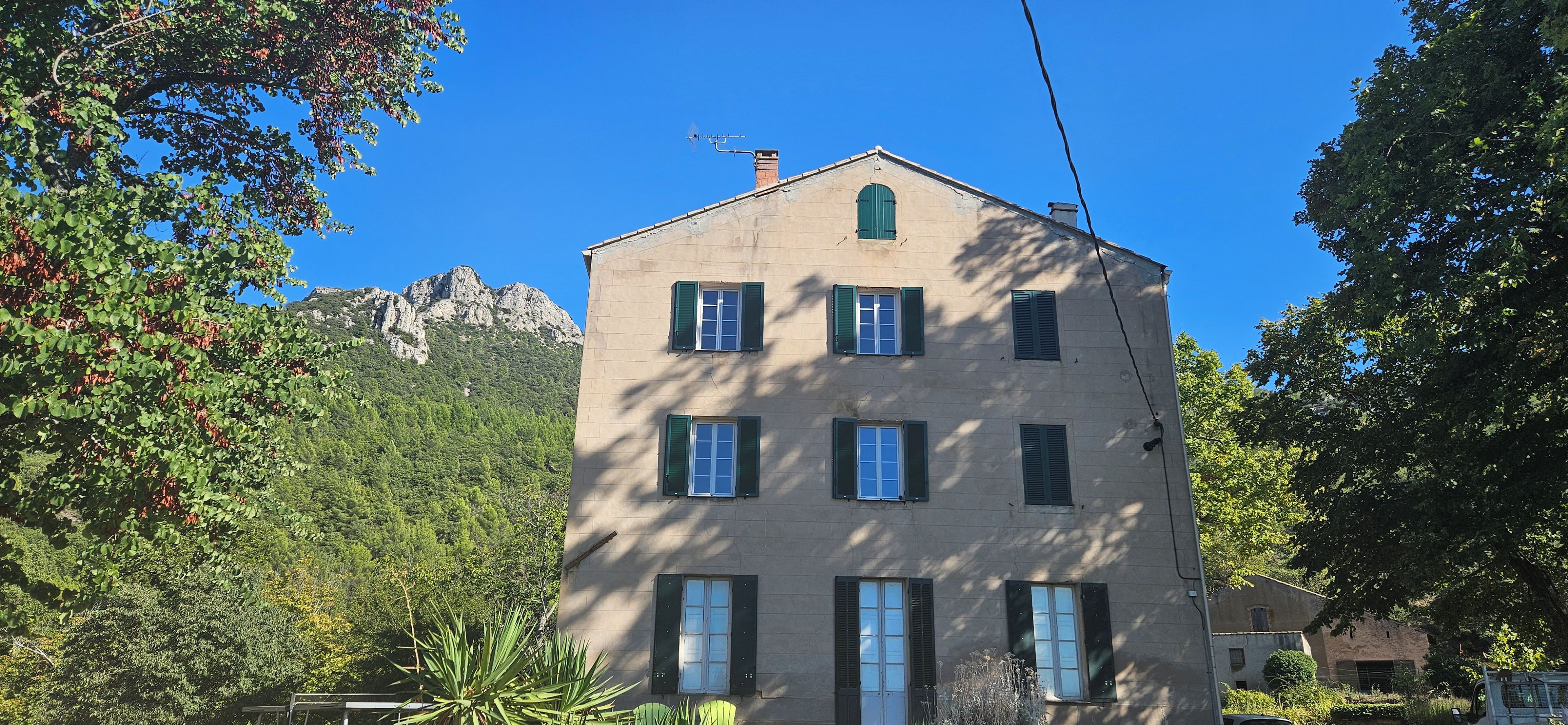 A multi-story building with a symmetrical facade, multiple windows with shutters, and a chimney.