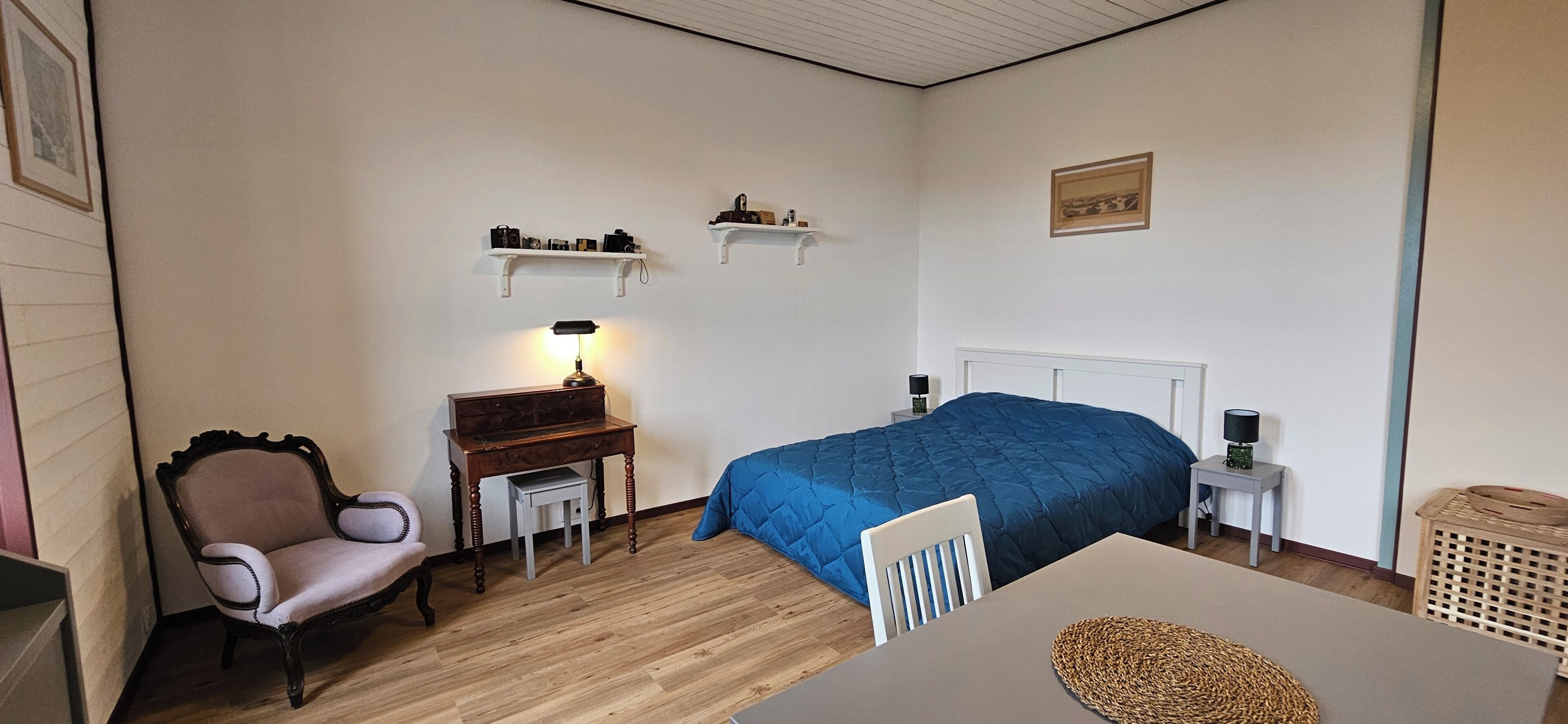 Een kamer met een bed, een bureau, een stoel en een lamp.