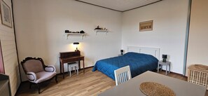 Quarto com cama, escrivaninha, cadeira e abajur.