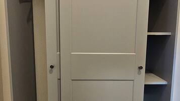 A grey wardrobe with a door, two shelves, and a hanging rod.
