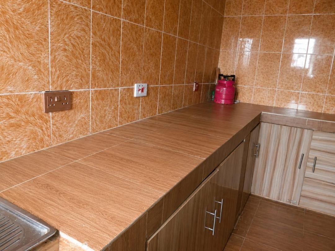 Cuina amb taulell marró, armaris de fusta i salabost a la paret.