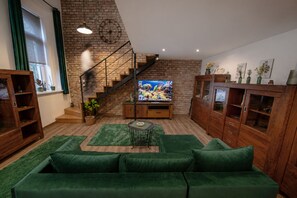 A living room with a green sofa, wooden cabinets, a staircase, and a television. - Cozy loft bedroom apartment in gorgeous Budapest (Budapest)