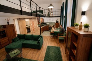 Ein modernes Interieur mit einem grünen Sofa, einem Esstisch und einer Küchenzeile.