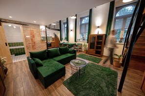 Ein modernes Wohnzimmer mit einem Ecksofa, einem kleinen runden Tisch und einem grünen Teppich.