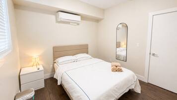Ein Hotelzimmer mit Bett, Nachttisch, Lampe, Spiegel und einer Tür.
