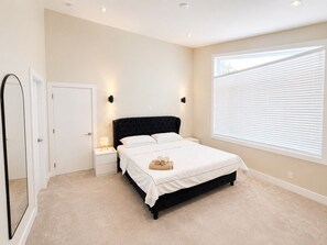 A bedroom with a bed, bedside tables, a mirror, and a window with blinds.