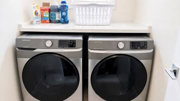 A laundry area with two Samsung washing machines and a basket on the countertop.