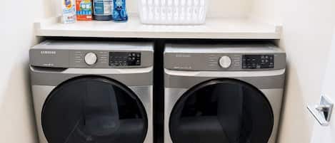 A laundry area with two Samsung washing machines and a basket on the countertop.