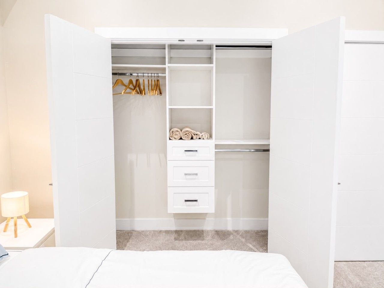 A white walk-in closet with shelves, drawers, and hanging space.