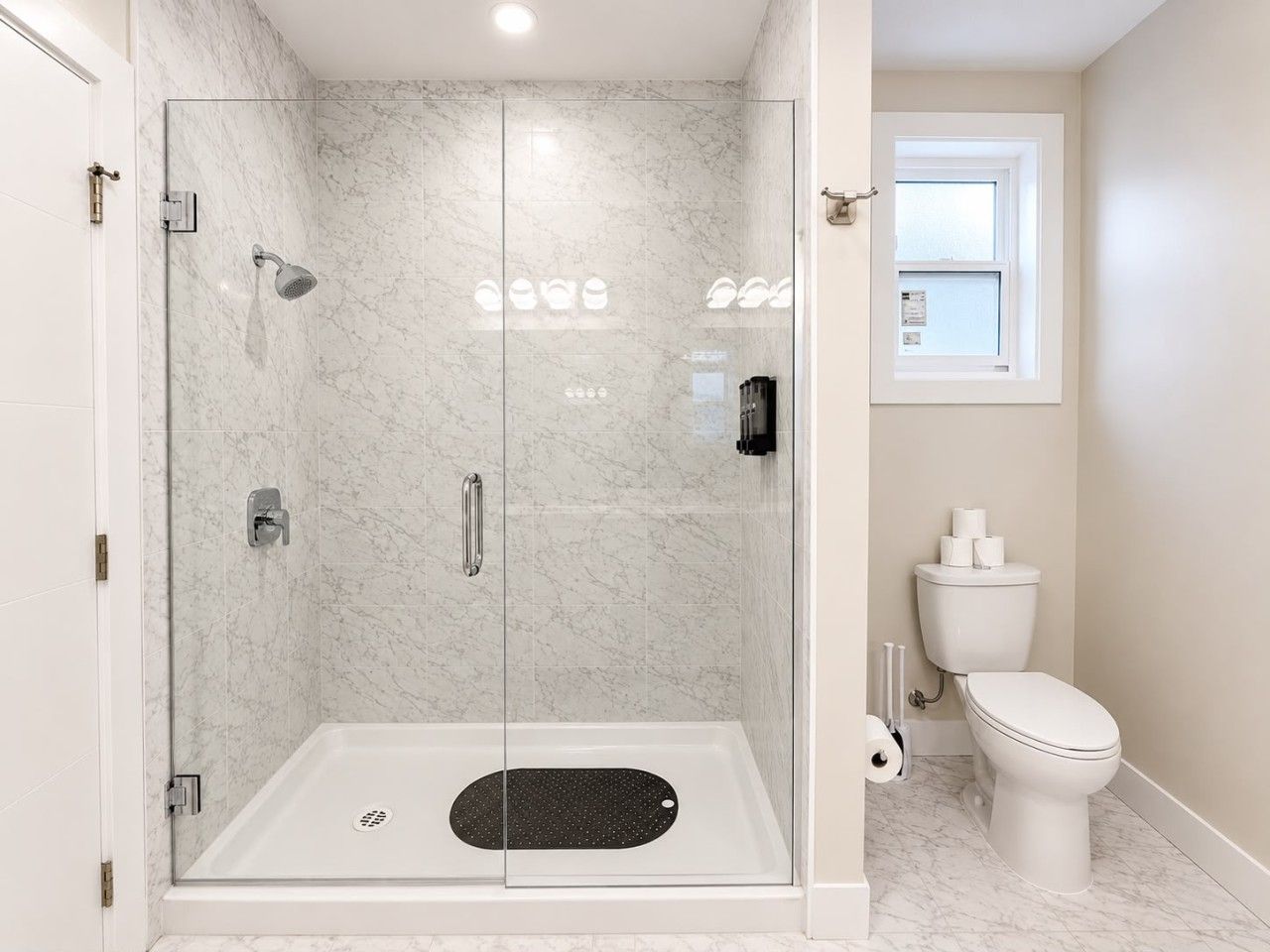 Une salle de bain moderne avec une douche à parois de verre, des toilettes et une fenêtre.