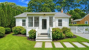 A single-story house with a front porch, a chimney, and a white picket fence. - Completely Renovated Sag Harbor Cottage with Lush Gardens, Pergola, and... (Sag Harbor)