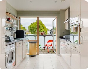 Eine moderne Küche mit Waschmaschine, Kaffeemaschine und einer Essecke mit einem roten Stuhl.