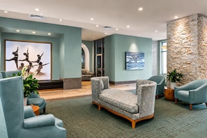 Eine moderne Lobby mit Sitzbereichen, einem großen Kunstwerk und einer Wand mit Steinverkleidung.