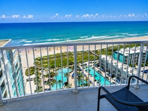 Ein Balkon mit Blick auf einen Strand und einen Poolbereich.