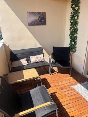 A balcony with a sofa, chairs, and a small table. - Bright 4-bedroom apartment with 2 bathrooms, a large balcony, and parking (Le Mans)