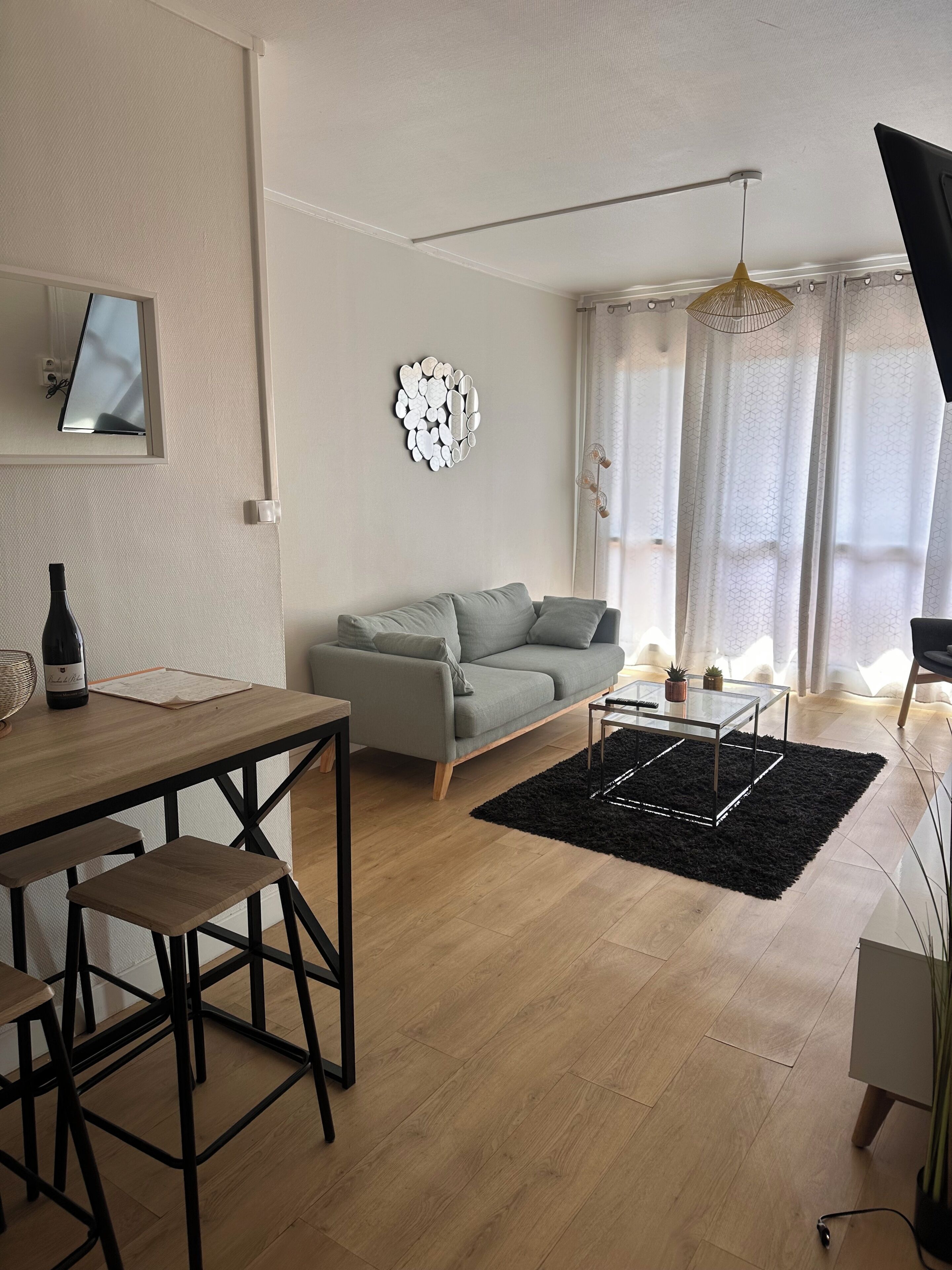 A modern living room with a grey sofa, a glass coffee table, and a black rug.