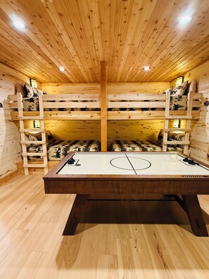 A wooden room with bunk beds, a ping pong table, and a wooden floor. - Deer Creek Lodge -12 min. to YNP+Hot tub+AC+Sauna Sleeps 26 (Island Park)
